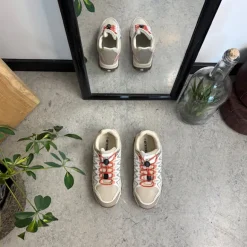 Fleksible beige sneakers med elastiksnørebånd.