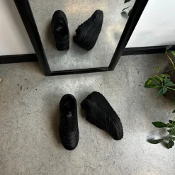 Sort sportssko med svangstøtte og gængesål.