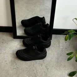 Sort sportssko med svangstøtte og gængesål.