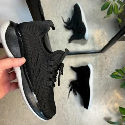 Sorte strikkede slip on sko med en fast kant i åbningen.