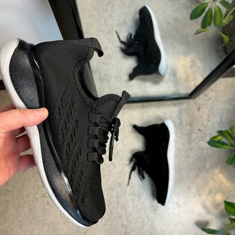 Sorte strikkede slip on sko med en fast kant i åbningen.