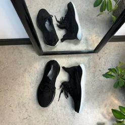 Sorte strikkede slip on sko med en fast kant i åbningen.